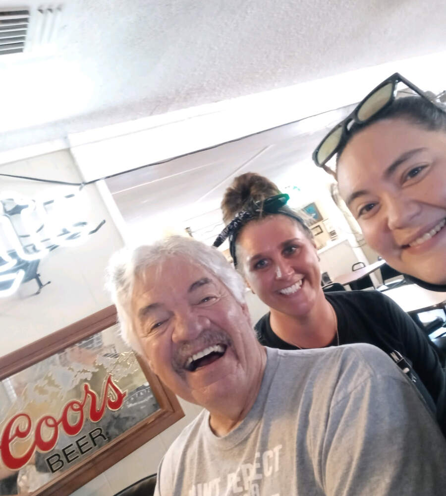 Server laughing with longtime regulars in the dining room at The Point Restaurant Perdido